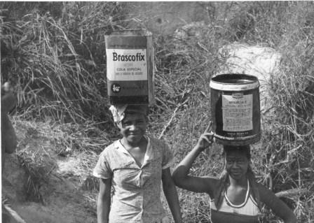 Mulheres carregando latas d'água